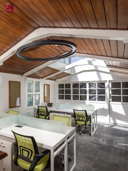 The main co-working area in the repurposed attic, featuring modern workstations and lighting that respects the original sloped roof structure.