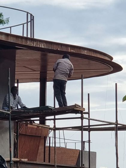 (Duplicate of 88) Workers on the scaffolding give a sense of scale to the large, sweeping canopy of the roof, a testament to the human effort required to realize an architectural vision.