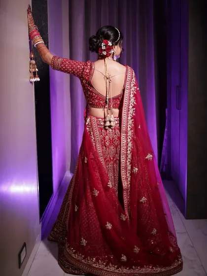 A stunning back shot of the bride, showing off her elegant bun, the back design of her blouse, and the fall of her lehenga.