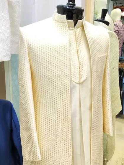 This open sherwani-jacket concept in a subtle cream fabric is a great choice for the groom. The textured jacket is layered over a simple matching kurta, offering a look of understated elegance.