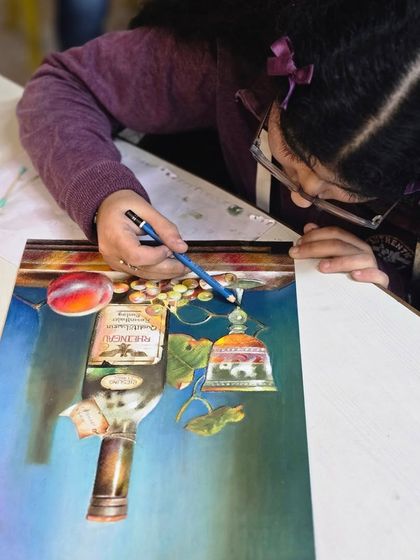 An overhead view of the young artist working on her still life, demonstrating the careful planning and execution that goes into her artwork.