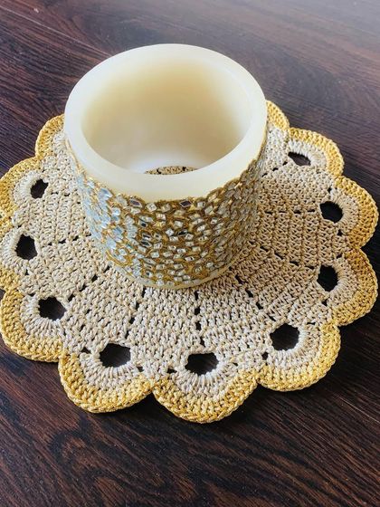 This doily in a natural beige color has a simple yet elegant design with a scalloped, openwork border. It's shown here under a mosaic candle holder.