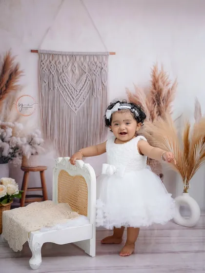 A heart-melting smile from the birthday girl. These moments of pure happiness are what make first birthday photoshoots so special.
