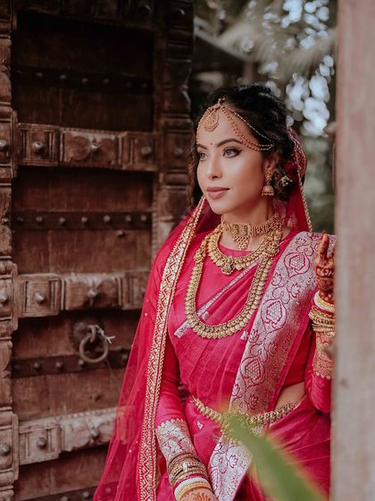 A stunning portrait of a South Indian bride in a vibrant pink saree, adorned with traditional gold jewelry.