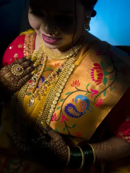 A dramatic and artistic bridal portrait using shadows and light to highlight the intricate embroidery of her saree and her beautiful jewelry.