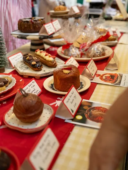 A close-up of our Christmas pop-up table, laden with treats like our Maska Rum Ball Bauble, Strawberry Croissant Cake, and eclairs. It's a sweet lover's dream.