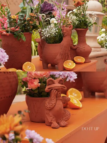 Playful and quirky details from a Haldi ceremony. Terracotta planters shaped like animals are filled with flowers and placed amongst fresh oranges, adding a touch of whimsy and fun to the decor.