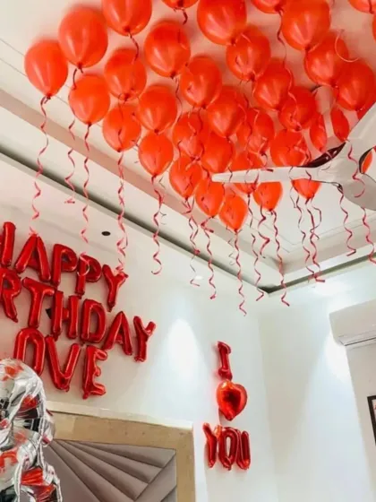 A view of the red balloons covering the ceiling, each with a dangling ribbon, creating a festive canopy over the room.