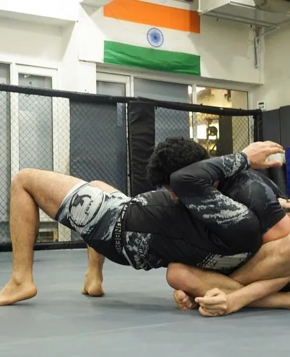 A student attempts a back-take from a turtle position. This is a key transition in jiu-jitsu, moving from a neutral or bad spot to an attacking one.