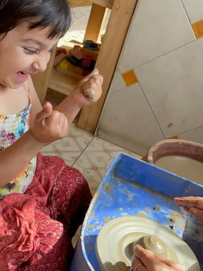 The thrill of seeing the clay take shape. This girl's expression of pure joy is a common sight in our pottery corner.