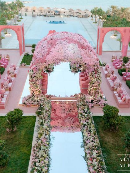 An aerial view of the 'Echoes of Pink' wedding setup, showing the magnificent floral mandap and the surrounding seating. The design was inspired by Qatar's architecture and the bride's favorite color.