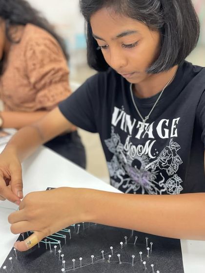 A close-up of the weaving process, as this young artist brings her flower design to life with colorful thread.
