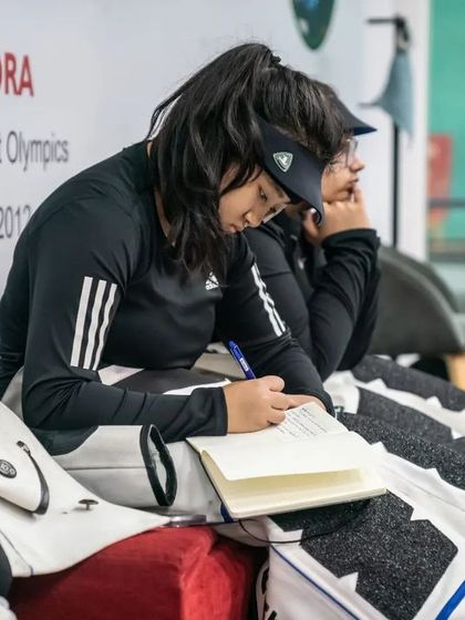 The mental game is just as important as the physical one. An athlete reviews her notes, analyzing her performance and strategizing for her next shots.