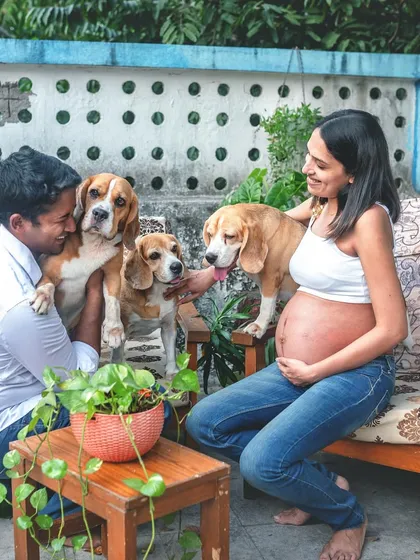 An expecting couple enjoys a relaxed moment on their home patio with their three Beagle dogs. This image shows how I lovingly include furry family members to capture the complete picture of your life.