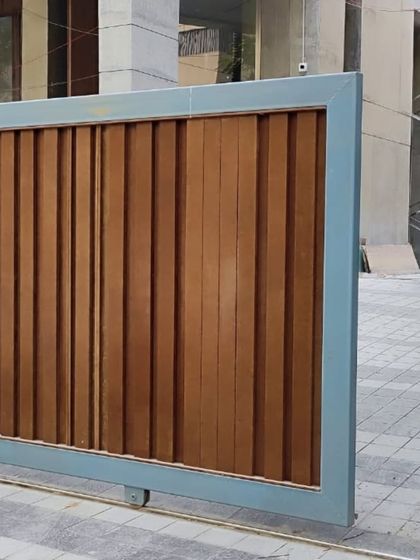 A sliding main gate featuring thick, vertical wooden planks within a sturdy metal frame. This design offers complete privacy and a robust, modern look.