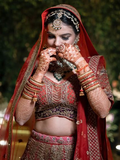 A candid moment of the bride adjusting her stunning necklace, her intricate mehndi and bridal bangles on full display.