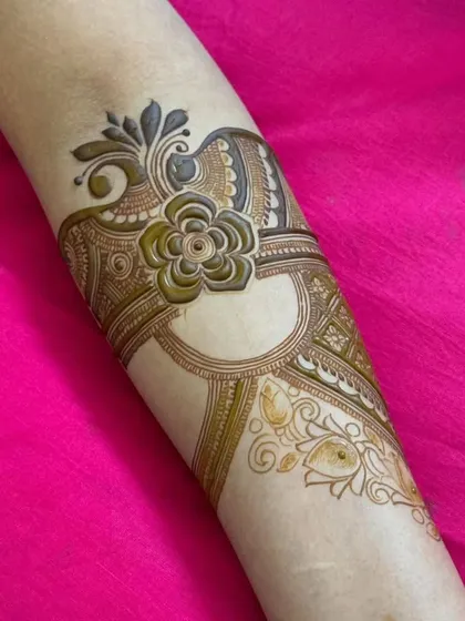 A delicate and modern arm piece featuring a large floral motif with fine, shaded details. This is a great example of contemporary henna art.