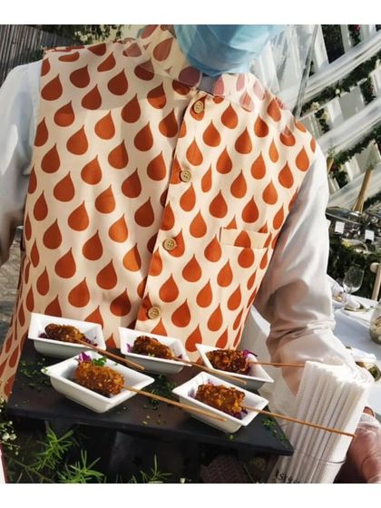 A server presents skewered kebabs in individual dishes. This image, a duplicate of ID 23, reinforces the theme of professional service and creative presentation.