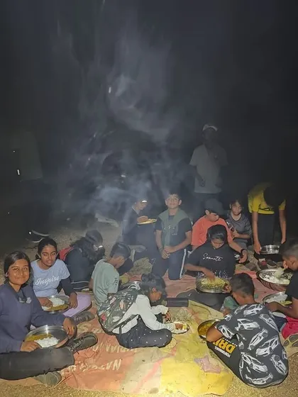 The camp circle enjoys a meal together around the smoky campfire, sharing stories and food.