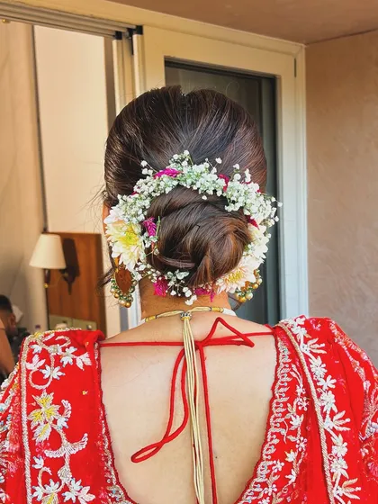 A close-up of a bridal bun adorned with a mix of baby's breath and other delicate white and pink flowers, perfect for a daytime wedding.
