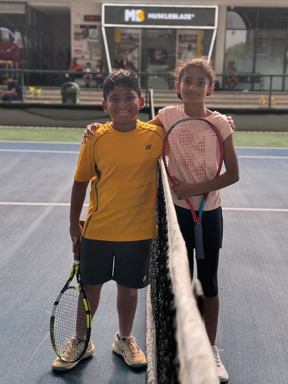 Two young players share a friendly moment at the net. Our group sessions are designed to help kids build friendships and learn the social aspects of the game.