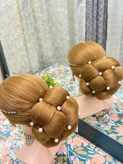 A large, woven bun created on a mannequin to showcase the technique. This style, decorated with pearls, is a popular choice for brides looking for a grand and voluminous updo.