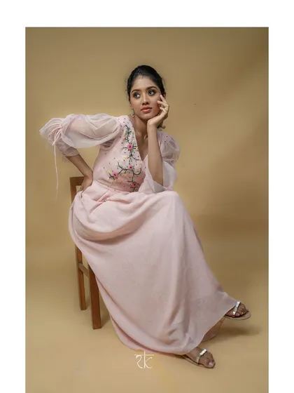 The gown's elegant silhouette and soft pink hue create a look of timeless femininity.
