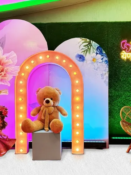 A beautiful celebration does not need a huge budget. This is an example of a compact and affordable baby shower setup that combines a cute teddy bear, a lighted arch, and colorful backdrops for a joyful and memorable event.