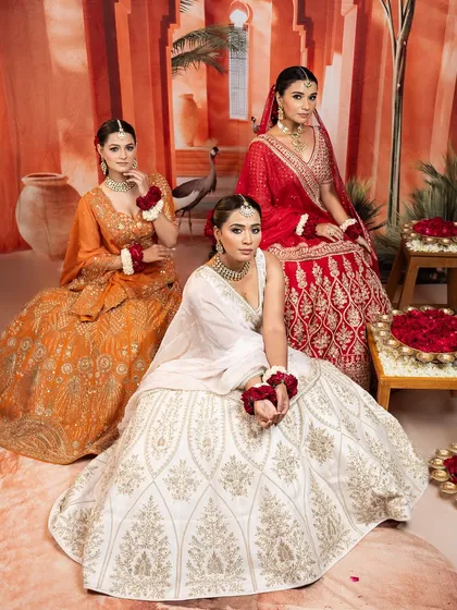 A glimpse of our bridal collection, featuring lehengas in classic red, warm orange, and serene white. Each piece is chosen for its unique embroidery, from dense zardozi to delicate threadwork.