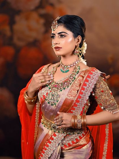 This image captures a bride in a moment of reflection. The soft, warm lighting and blurred floral background put all the focus on the intricate details of her attire and jewelry.