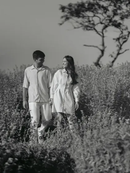 A serene walk through a field of flowers. In black and white, the texture of the plants and the quiet companionship of the couple become the central focus.
