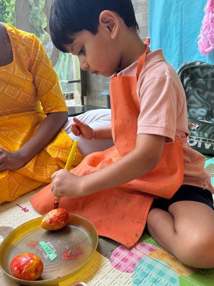 A young boy focused on painting Easter eggs. This classic activity is always a favorite and helps develop concentration and fine motor skills.