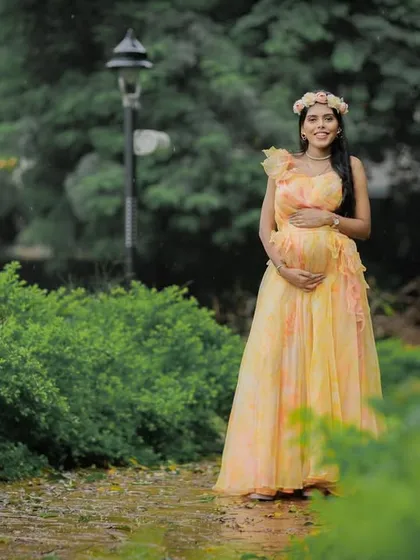 A lovely solo portrait of a mom-to-be walking through a garden path, looking happy and serene.