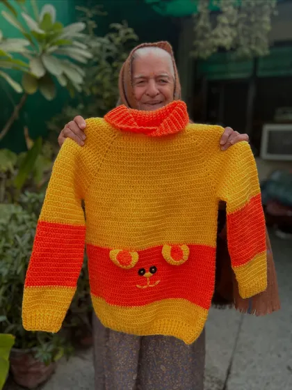 A cozy sweater with a friendly face. This turtleneck design in yellow and orange features a cute bear face, making it a fun and warm choice for chilly days.