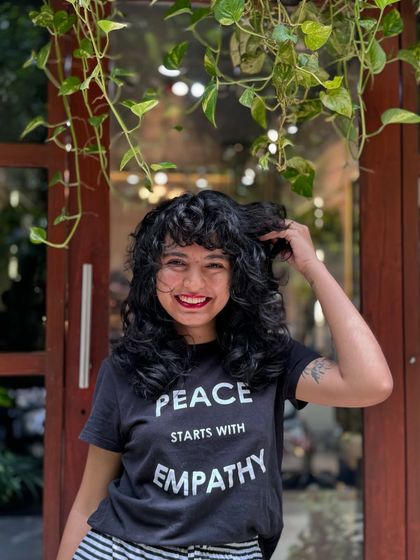 Curly bangs are the cutest! This client is radiating joy with her new fringe and layered cut that perfectly frames her smiling face.