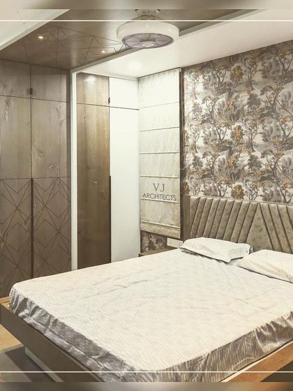 This bedroom features a sophisticated wallpaper with a classic floral pattern, paired with a modern, angular headboard. The combination of patterns and textures creates a rich, layered look.