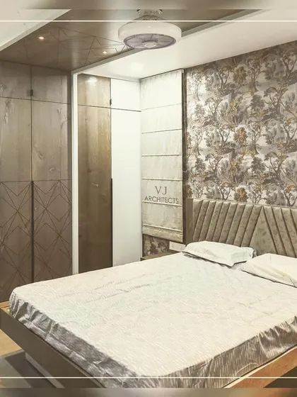 This bedroom features a sophisticated wallpaper with a classic floral pattern, paired with a modern, angular headboard. The combination of patterns and textures creates a rich, layered look.