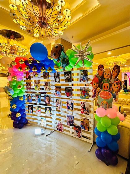 A creative Cocomelon-themed photo wall, allowing guests to see memories of the little one, framed by a colorful balloon arch.