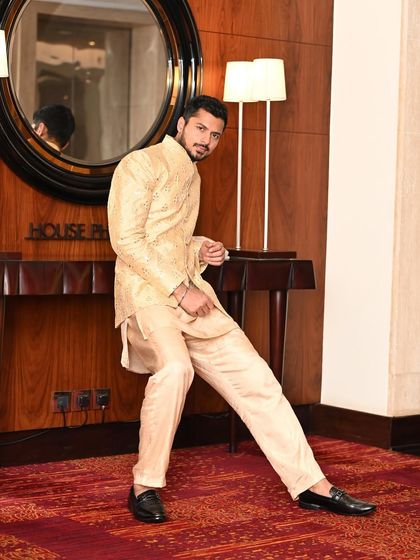 A dynamic pose in a golden, mirror-work ethnic jacket. This look is perfect for sangeets, weddings, and other festive celebrations.
