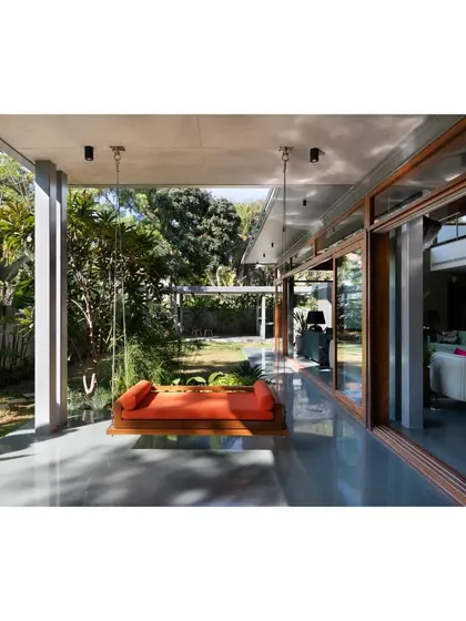 An orange swing on the verandah adds a pop of color and a sense of playful relaxation to the otherwise monolithic concrete structure.