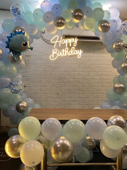 A close-up of the balloon arch and neon sign from the underwater theme. I use a mix of pastel blue, mint green, and chrome silver balloons, along with a cute seahorse foil balloon.
