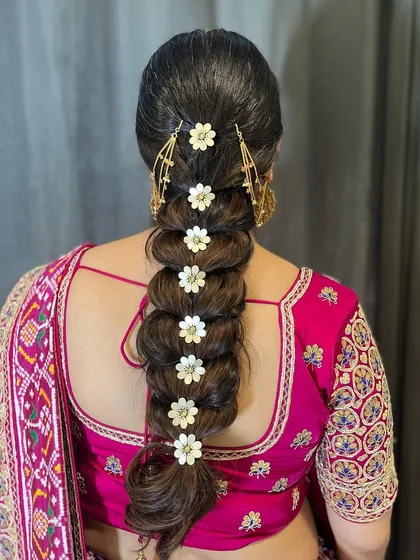 This voluminous pull-through braid is decorated with floral pins and a delicate hair chain. It's a dramatic and beautiful style that works wonderfully for a traditional ceremony like a patola.
