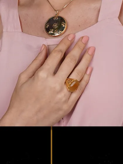 A close-up on a unique gold pendant with intricate carvings, paired with a matching ring.