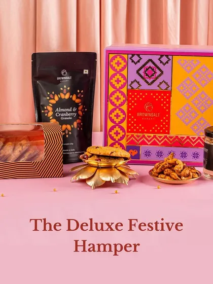 The Deluxe Festive Hamper offers a wonderful variety of our bestsellers. It includes our Almond & Cranberry Granola, assorted cookies, and a jar of Spiced Peri-Peri Cashews, all packed in a colorful and festive gift box.