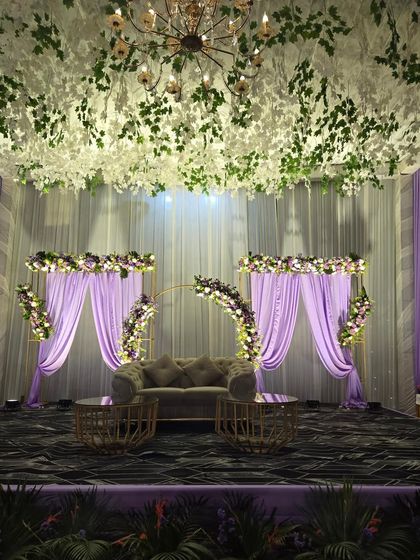 For a client who wanted a unique color theme, I designed this lavender wedding stage. The decor features a ceiling of hanging white flowers, purple drapes, and matching floral arrangements on the stage.
