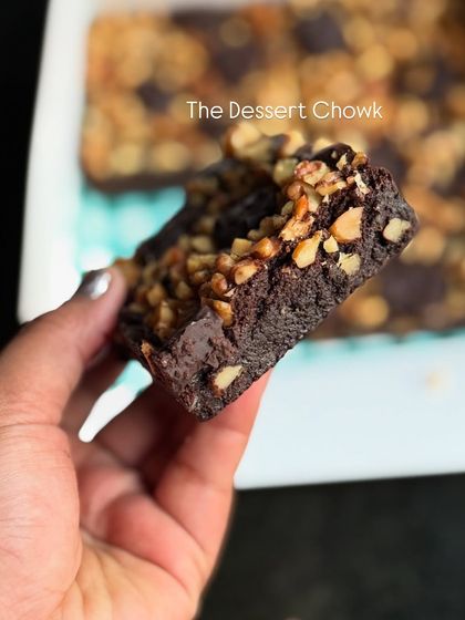A side view of a walnut brownie piece, showing the rich, dark chocolate base and the generous layer of chopped walnuts on top.