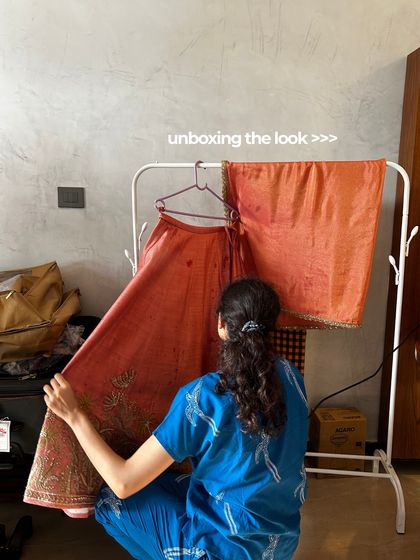 Unboxing the look. A behind-the-scenes peek at the bride's stunning coral lehenga before the main event.