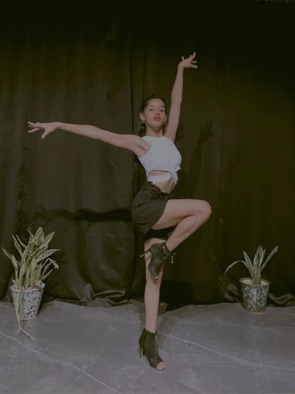 A simple, elegant pose in heels against a black curtain. This photo shows the classic lines and posture that are fundamental to both jazz and heels dance training.