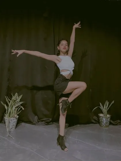 A simple, elegant pose in heels against a black curtain. This photo shows the classic lines and posture that are fundamental to both jazz and heels dance training.