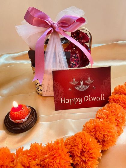 A charming mini basket hamper wrapped in pink ribbon and tulle. It's a small but heartfelt Diwali gift, perfect for distributing among a large group.